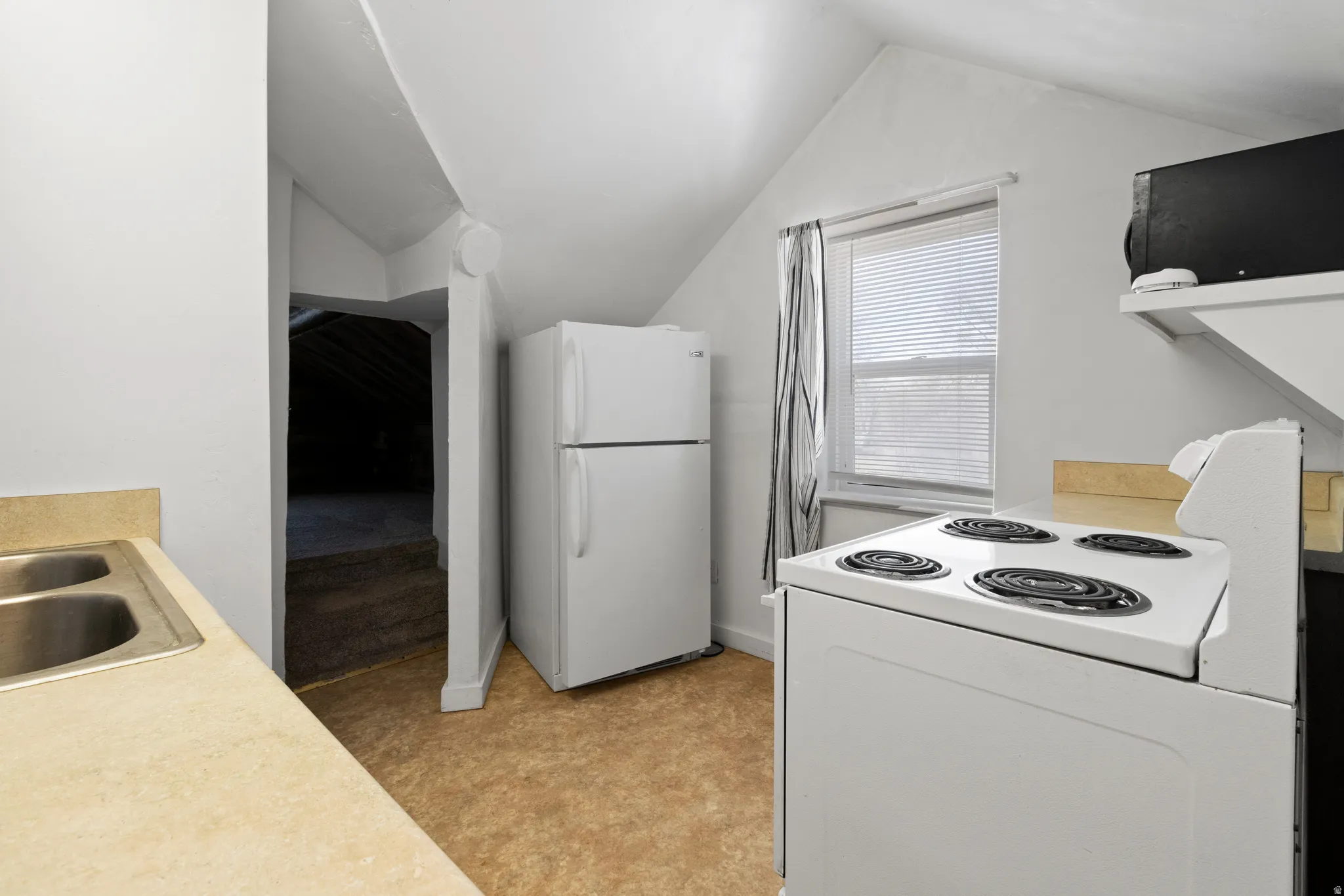 Kitchen with white appliances, light countertops, and light flooring