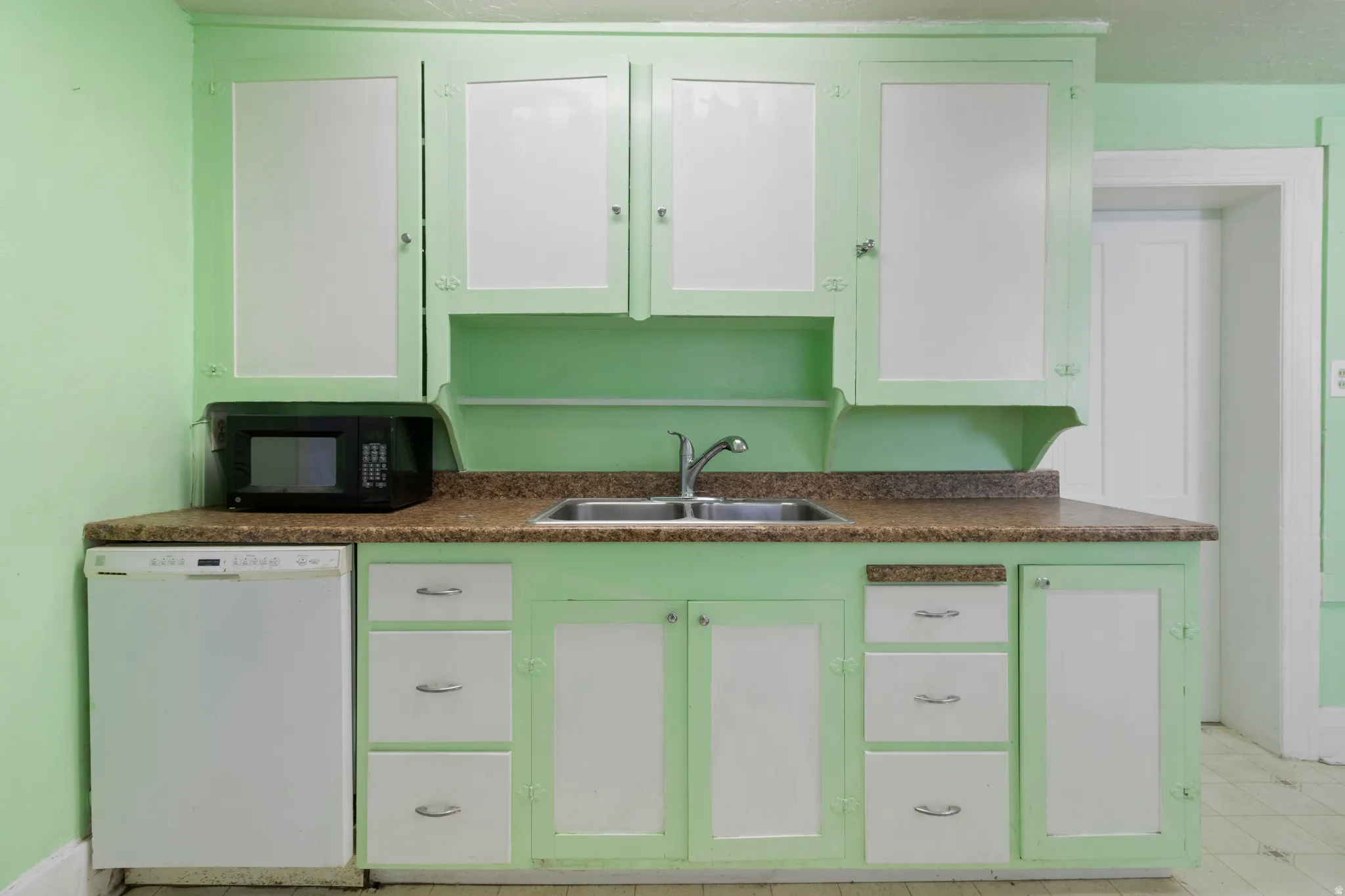 Kitchen with white cabinetry, dishwasher, black microwave, and dark countertops