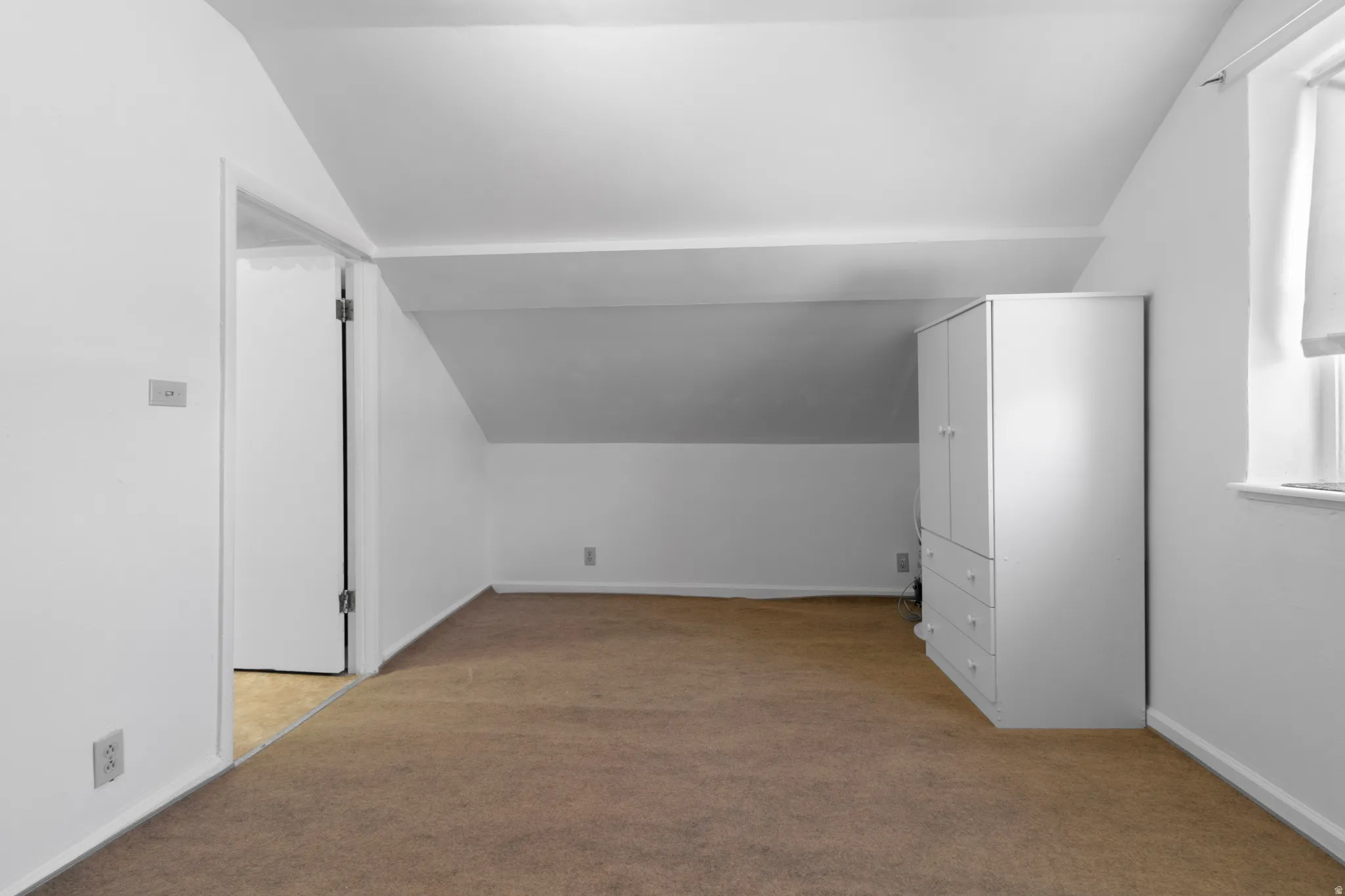 Additional living space featuring light colored carpet and lofted ceiling