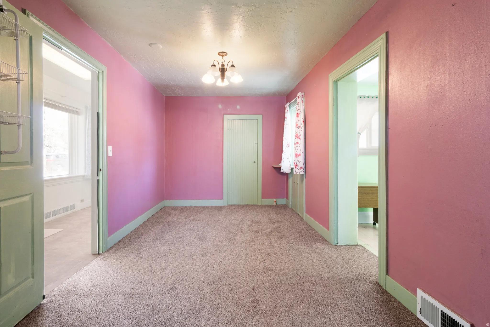 Spare room with light colored carpet, a textured ceiling, and hanging lights