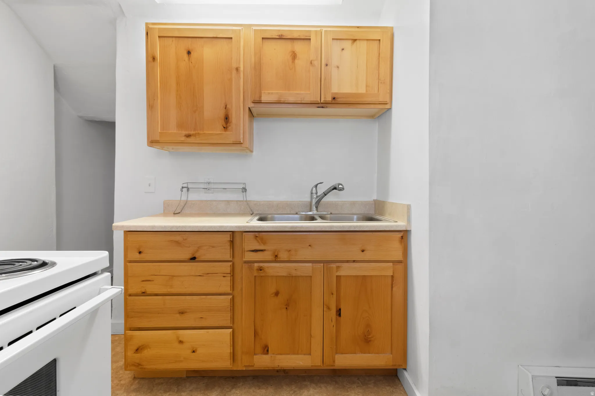 Kitchen with light countertops, light wood finish cabinetry, and white range with electric cooktop