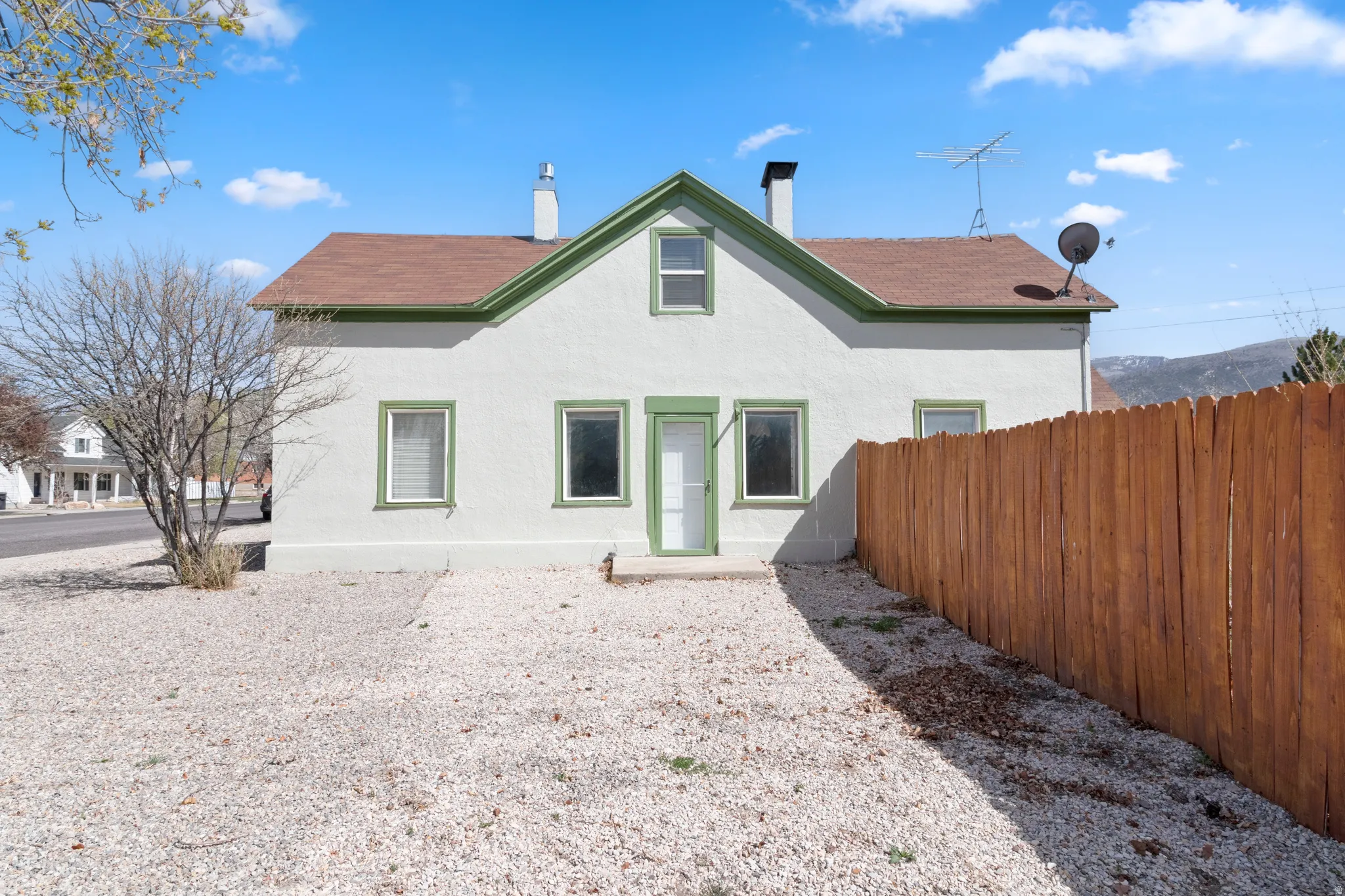 Back of house featuring a chimney and stucco siding