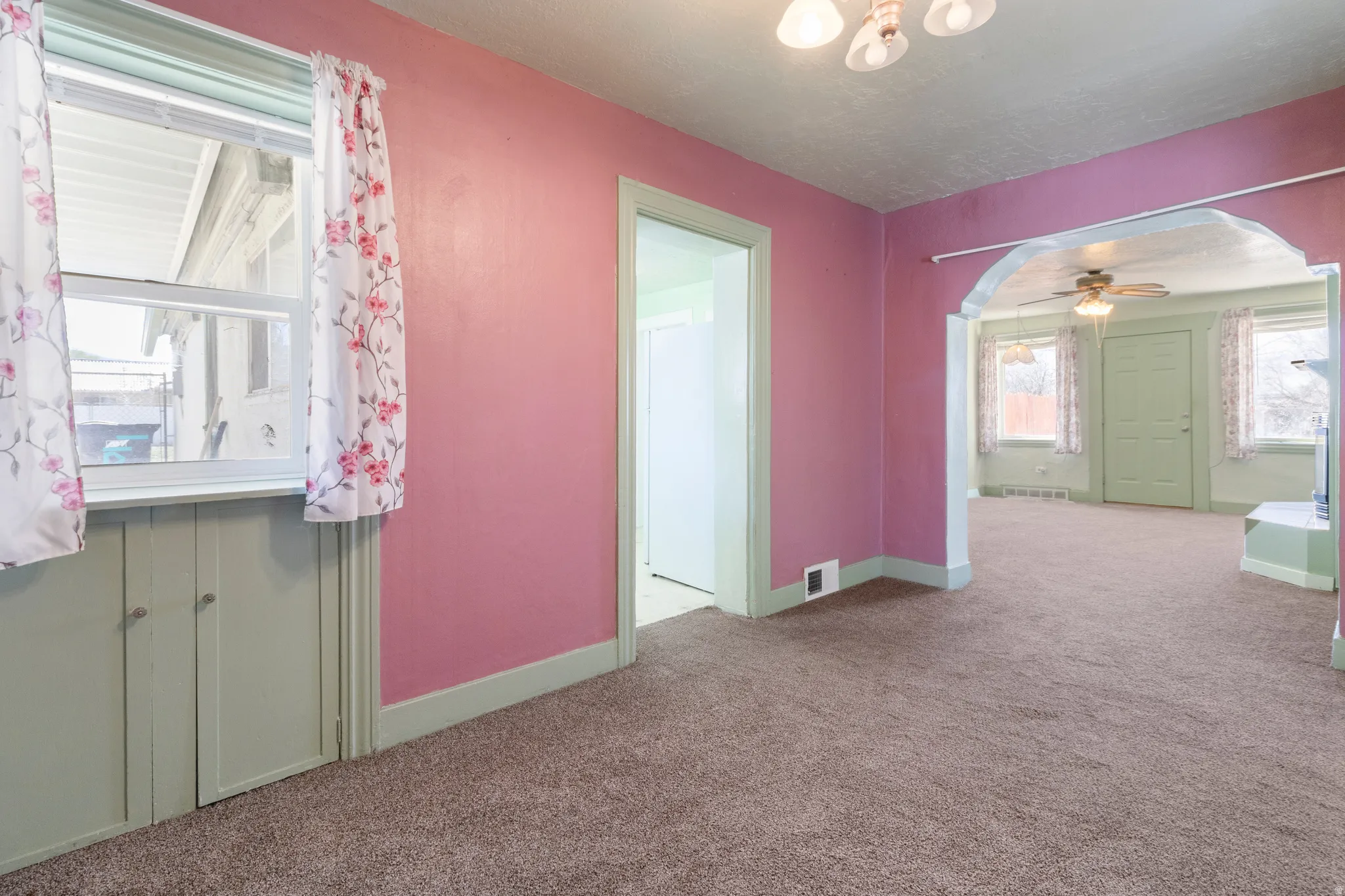 Empty room with arched walkways, carpet floors, and a ceiling fan