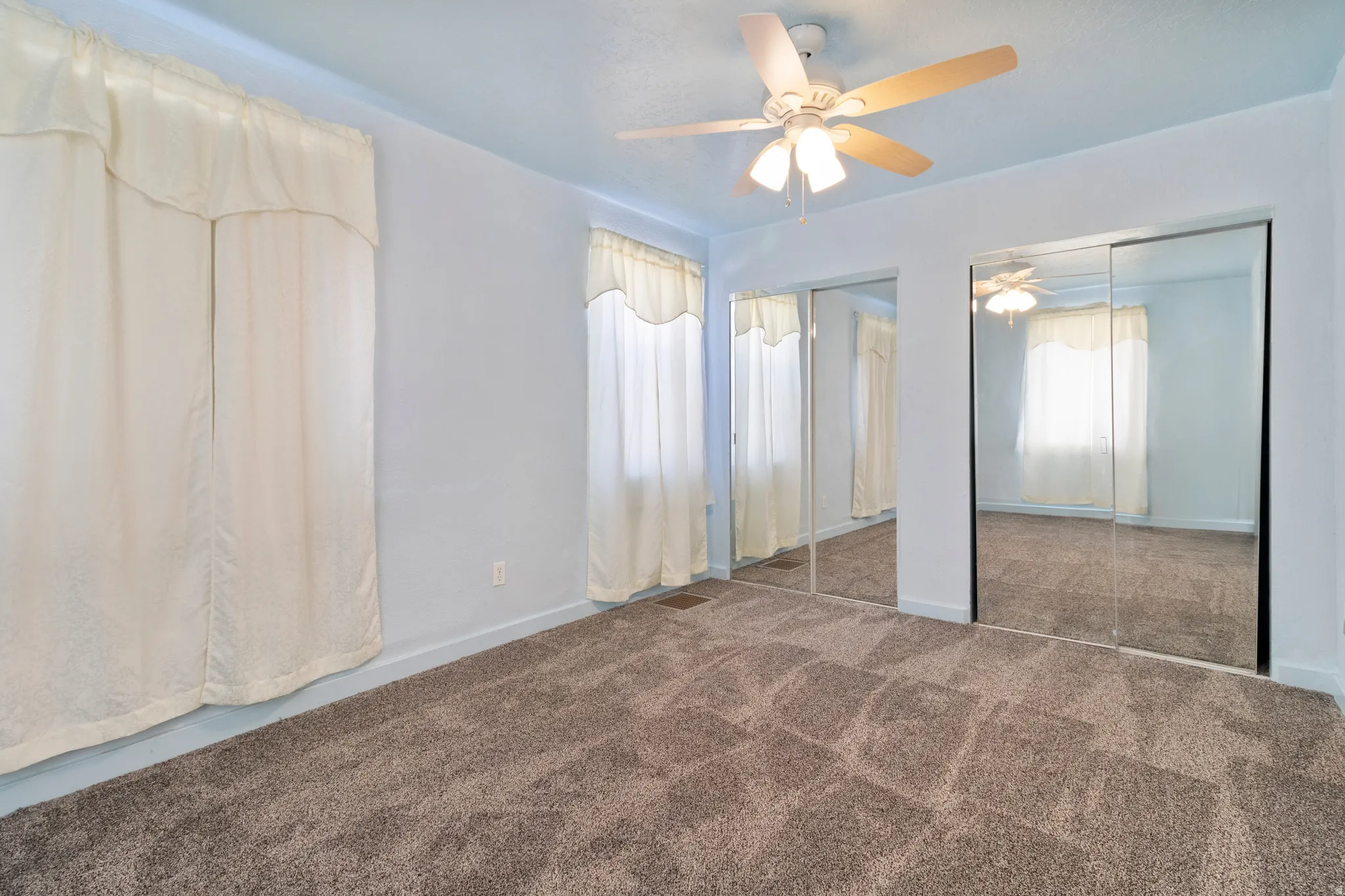 Unfurnished bedroom featuring multiple closets, carpet floors, and a ceiling fan
