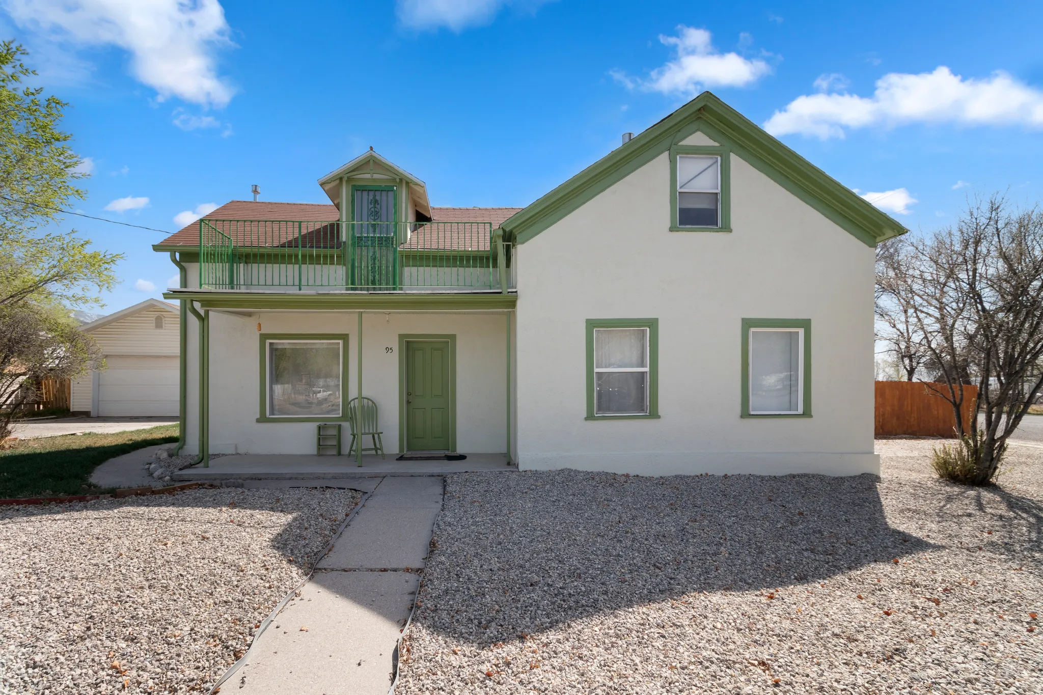 View of front of house featuring stucco siding, a balcony, and a porch