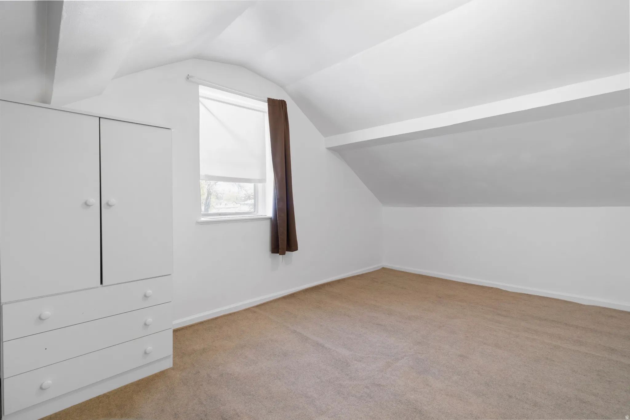 Bonus room with light colored carpet and baseboards