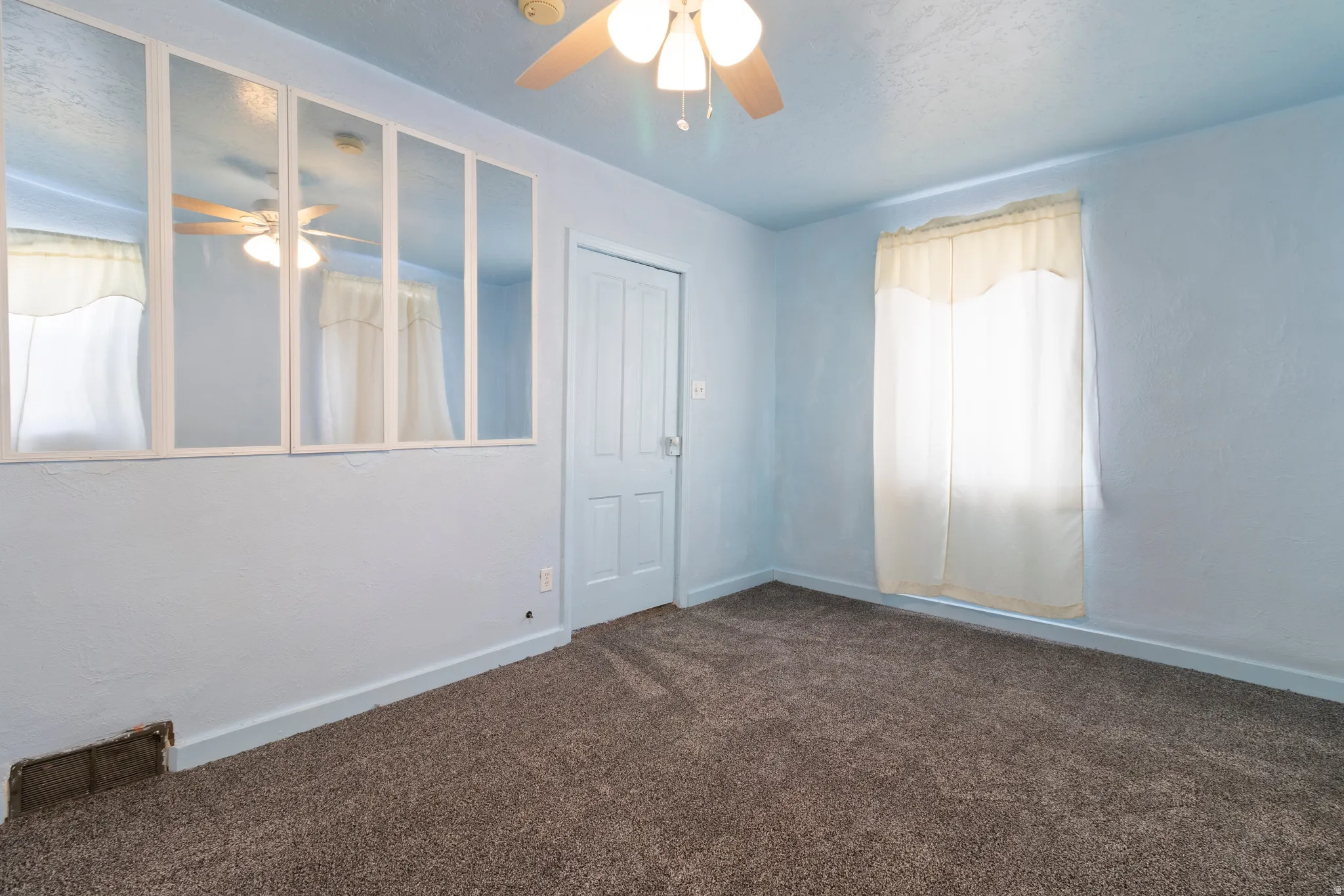 Unfurnished room featuring a ceiling fan and dark colored carpet