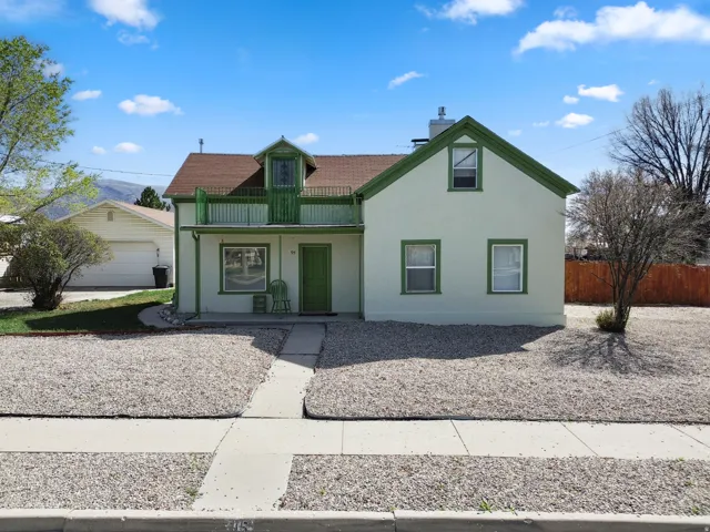 View of front of home with stucco siding, a balcony, and a chimney