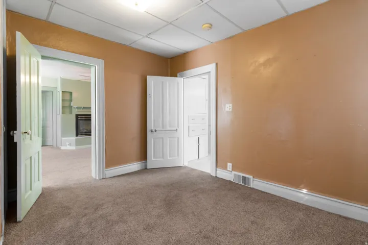 Unfurnished bedroom featuring carpet, a glass covered fireplace, and a paneled ceiling