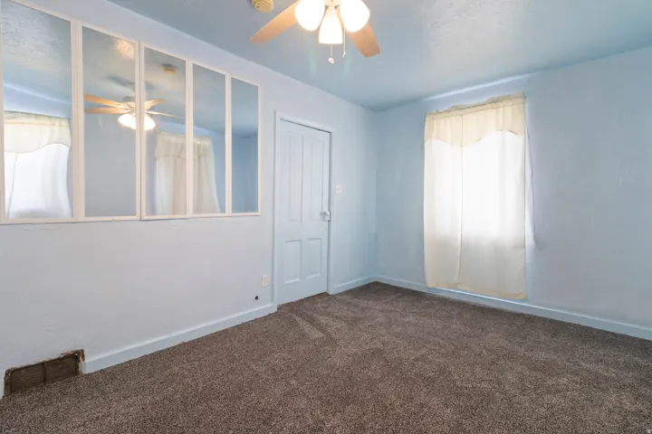 Unfurnished room featuring a ceiling fan and dark colored carpet
