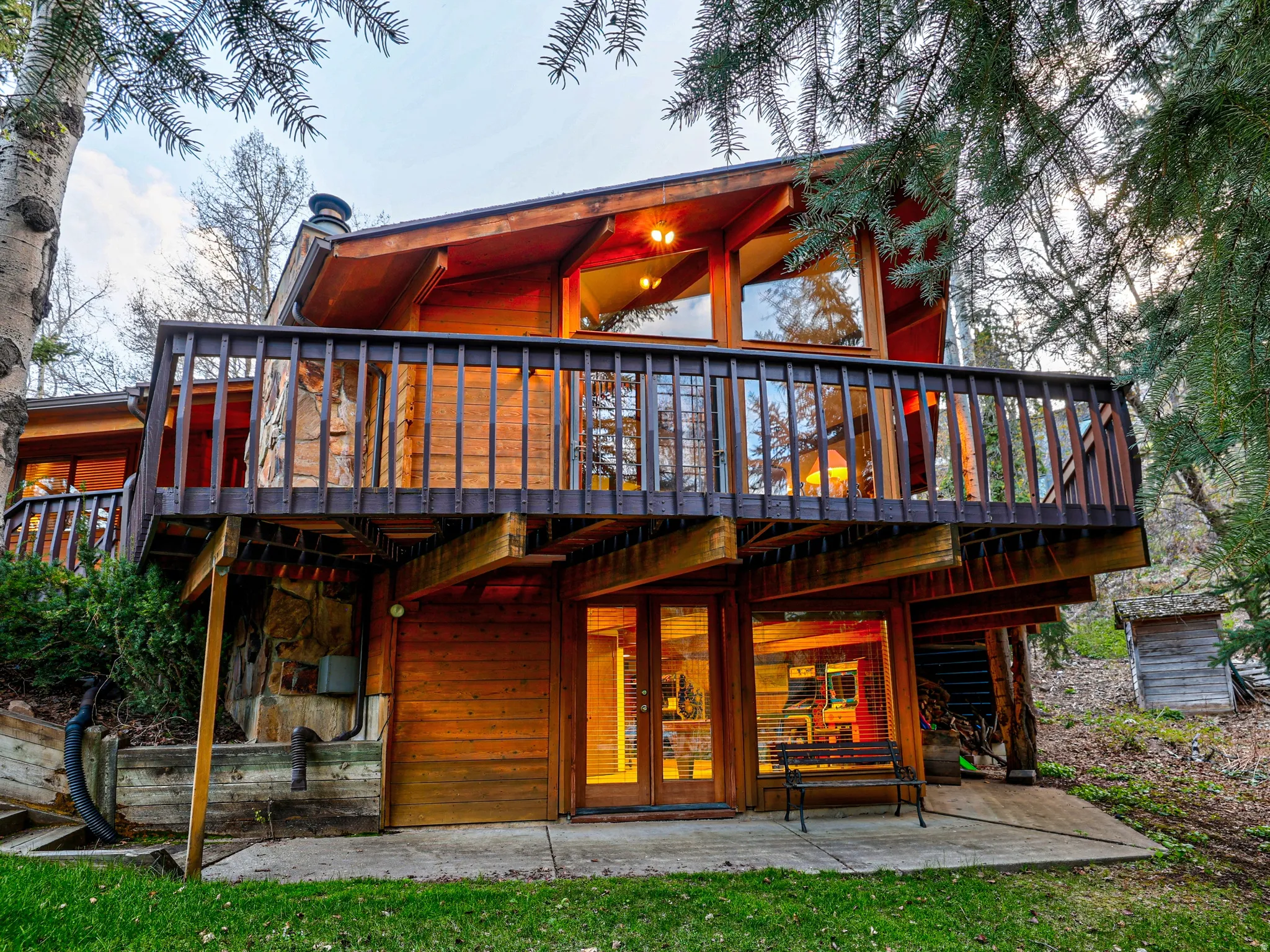 Classic mountain home at dusk featuring large wrap-around deck