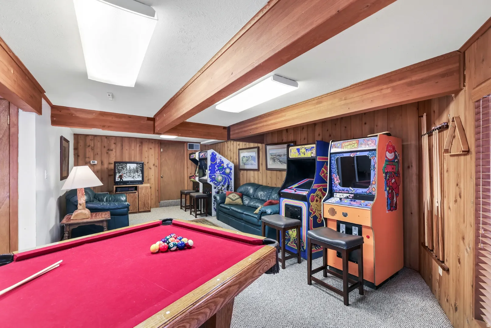 Rec room with billiards table, light colored carpet, beamed ceiling, and wooden walls