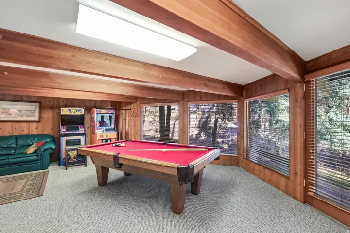 Recreation room featuring billiards table, light carpet, wood walls, beamed ceiling, and plenty of natural light