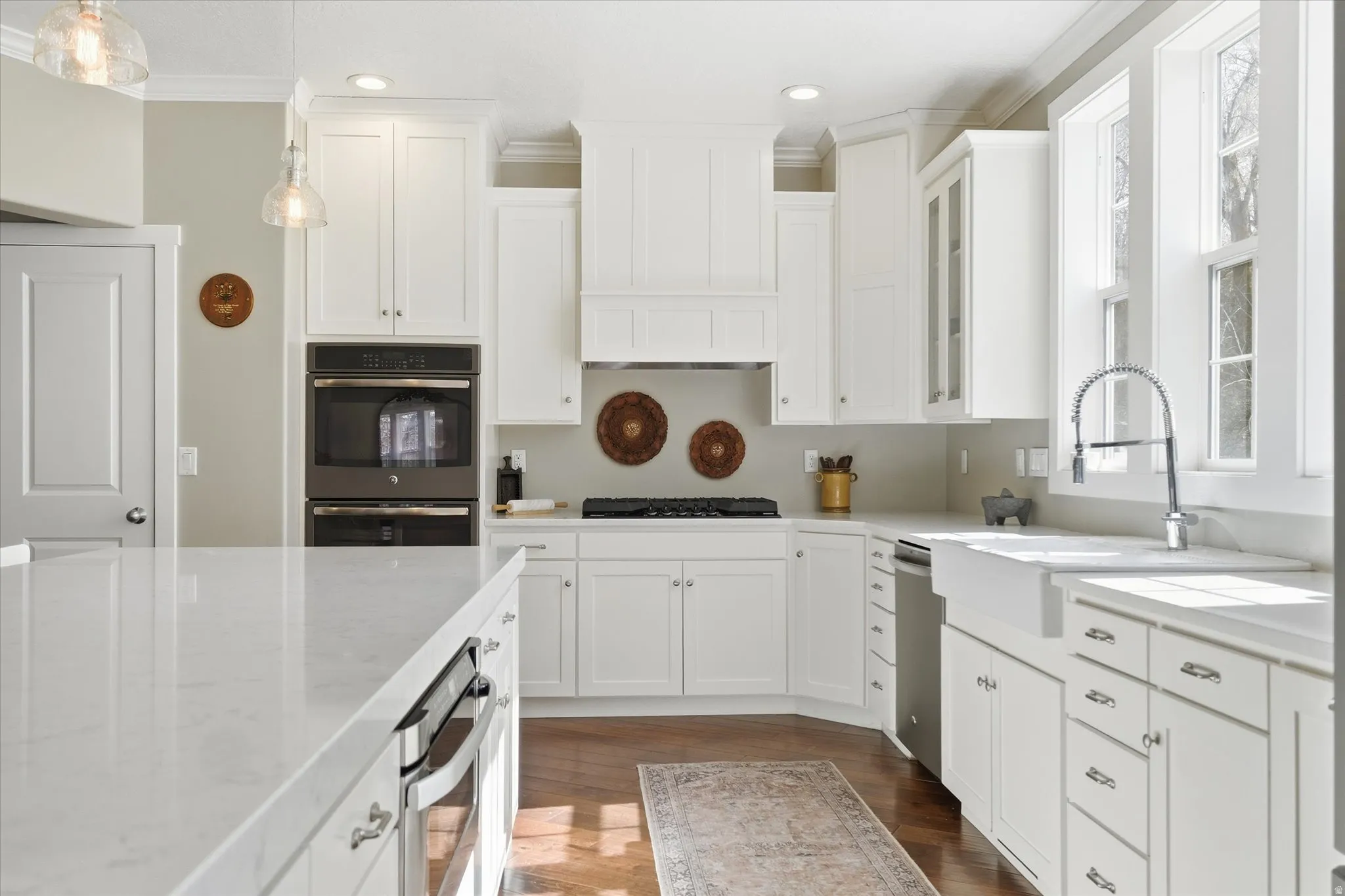 Kitchen with white cabinetry, stainless steel appliances, pendant lighting, and ornamental molding