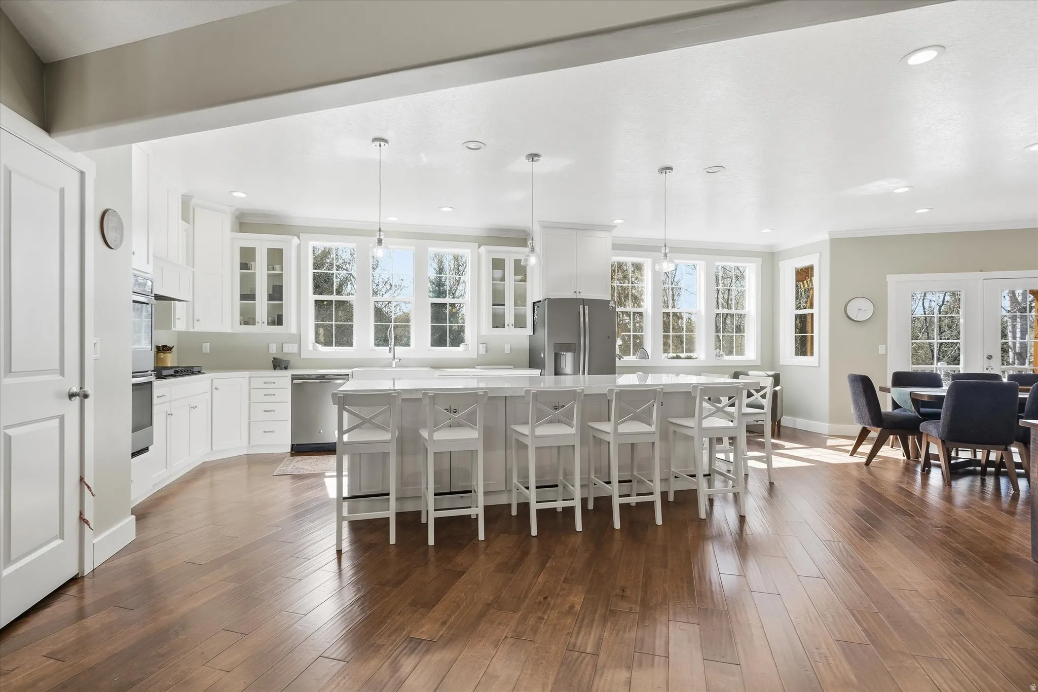Kitchen featuring glass fronted cabinets, a kitchen breakfast bar, white cabinetry, pendant lighting, and ornamental molding