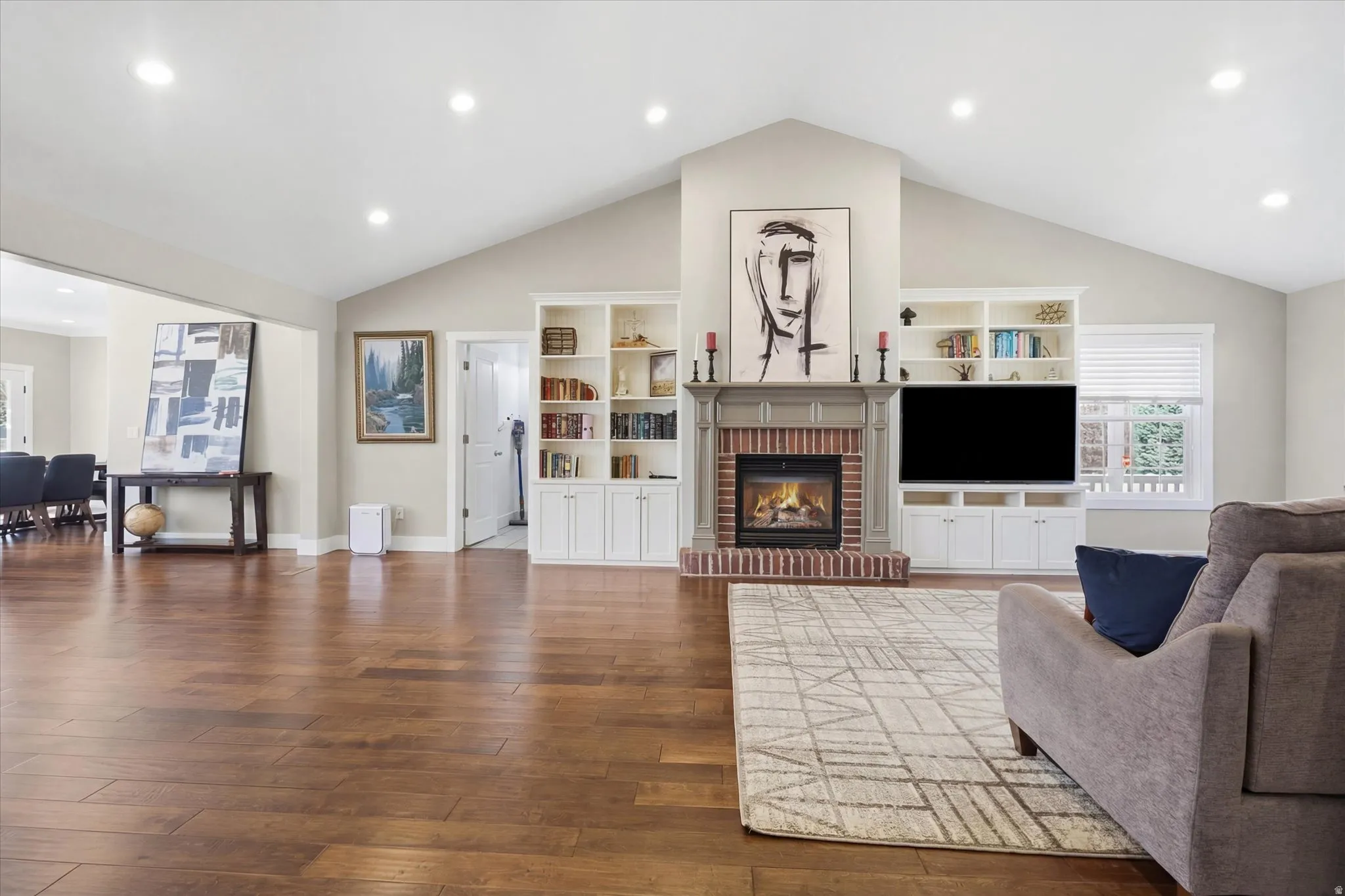 Living area with dark wood-style floors, recessed lighting, and a brick fireplace