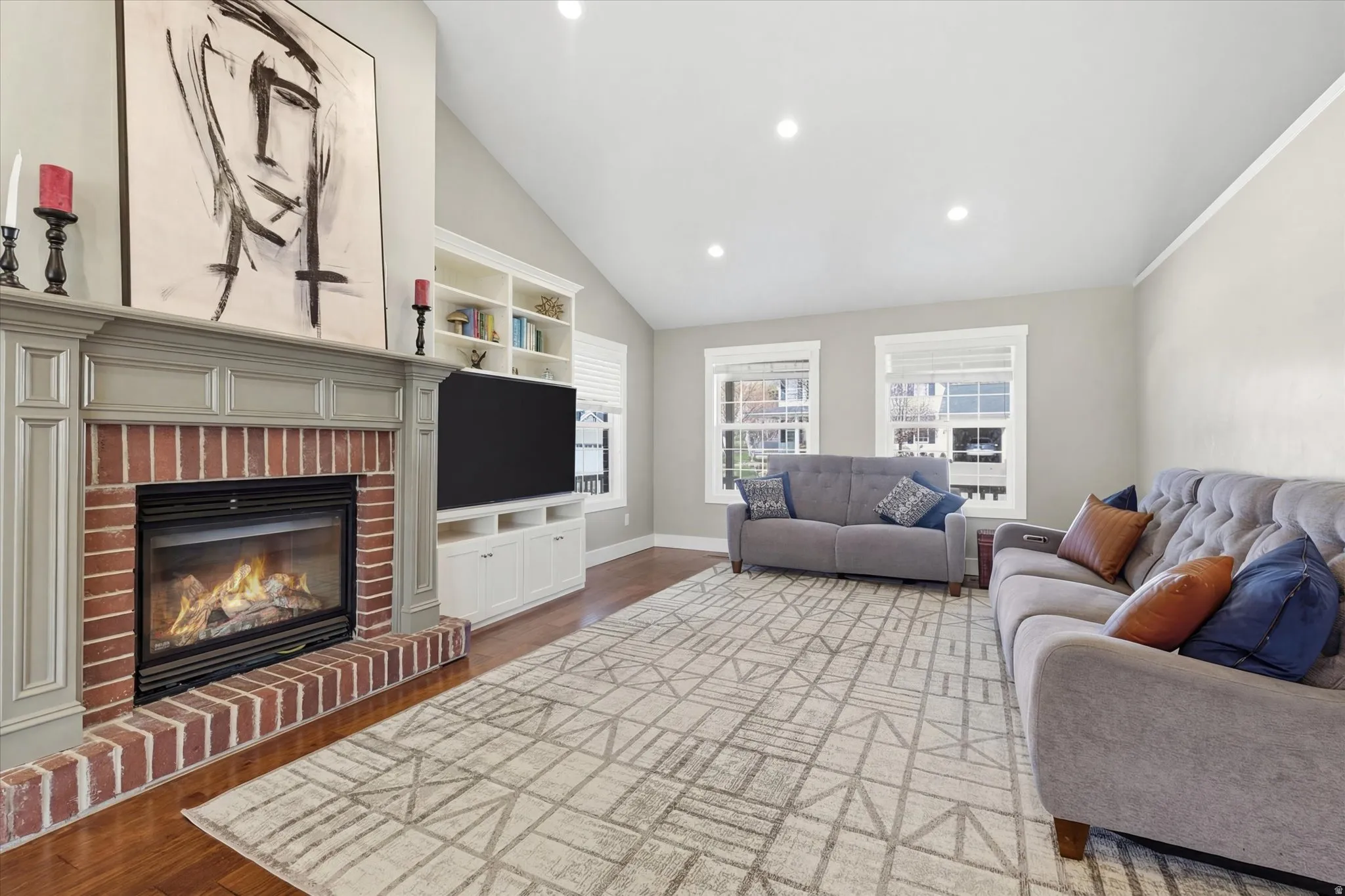 Living area featuring lofted ceiling, dark wood-style floors, plenty of natural light, a brick fireplace, and recessed lighting