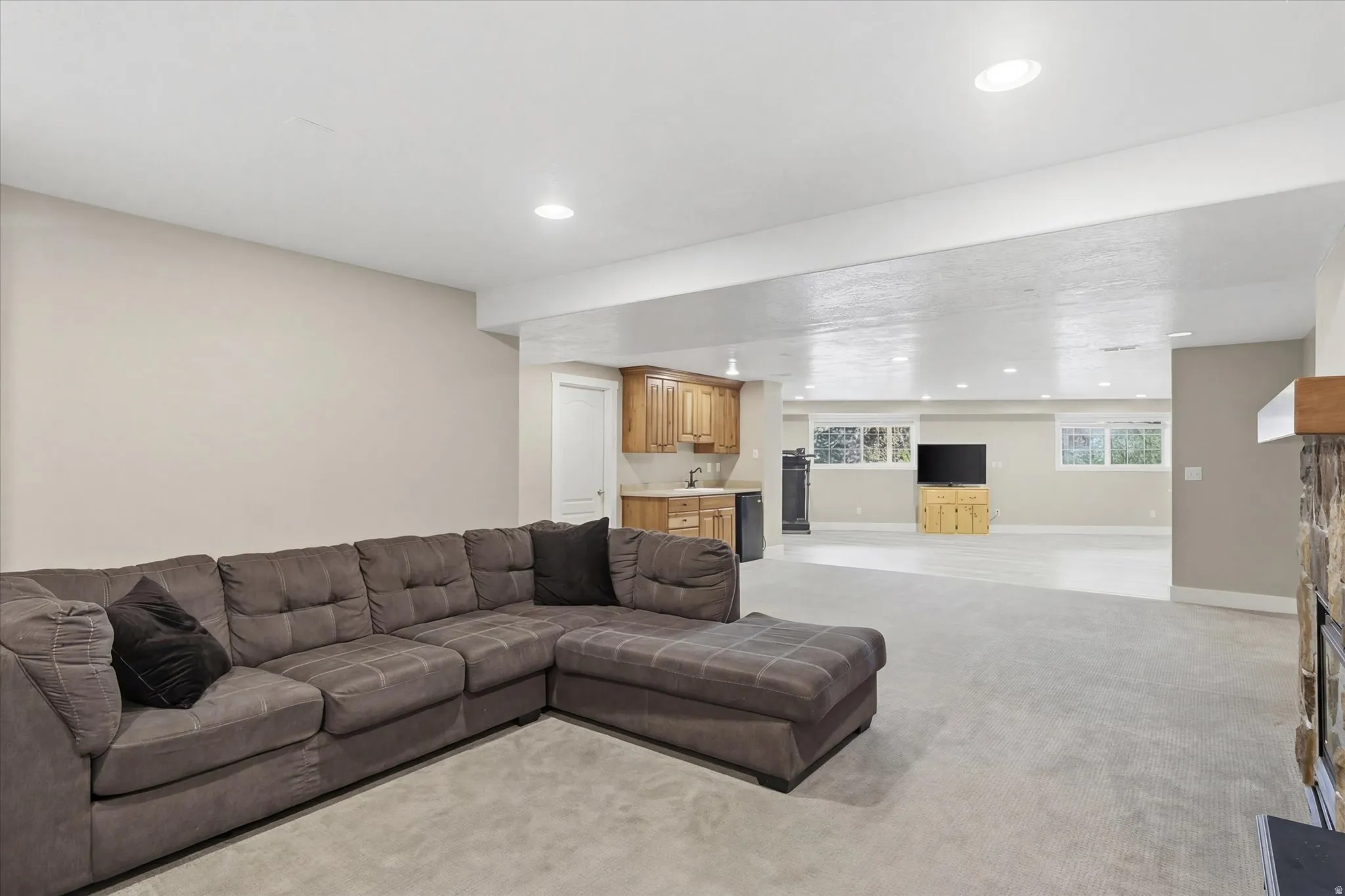 Living area featuring wet bar, light colored carpet, and recessed lighting
