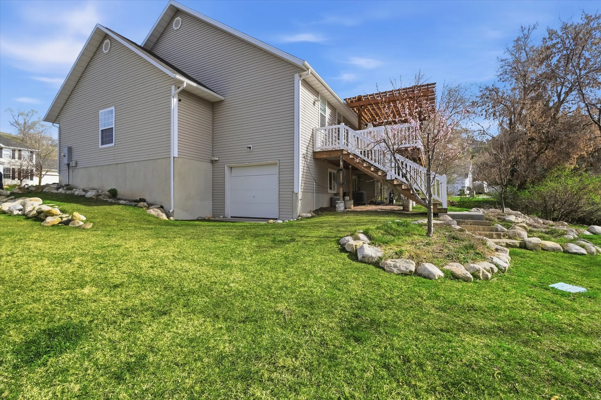 View of home's exterior featuring a garage, a wooden deck, and a yard