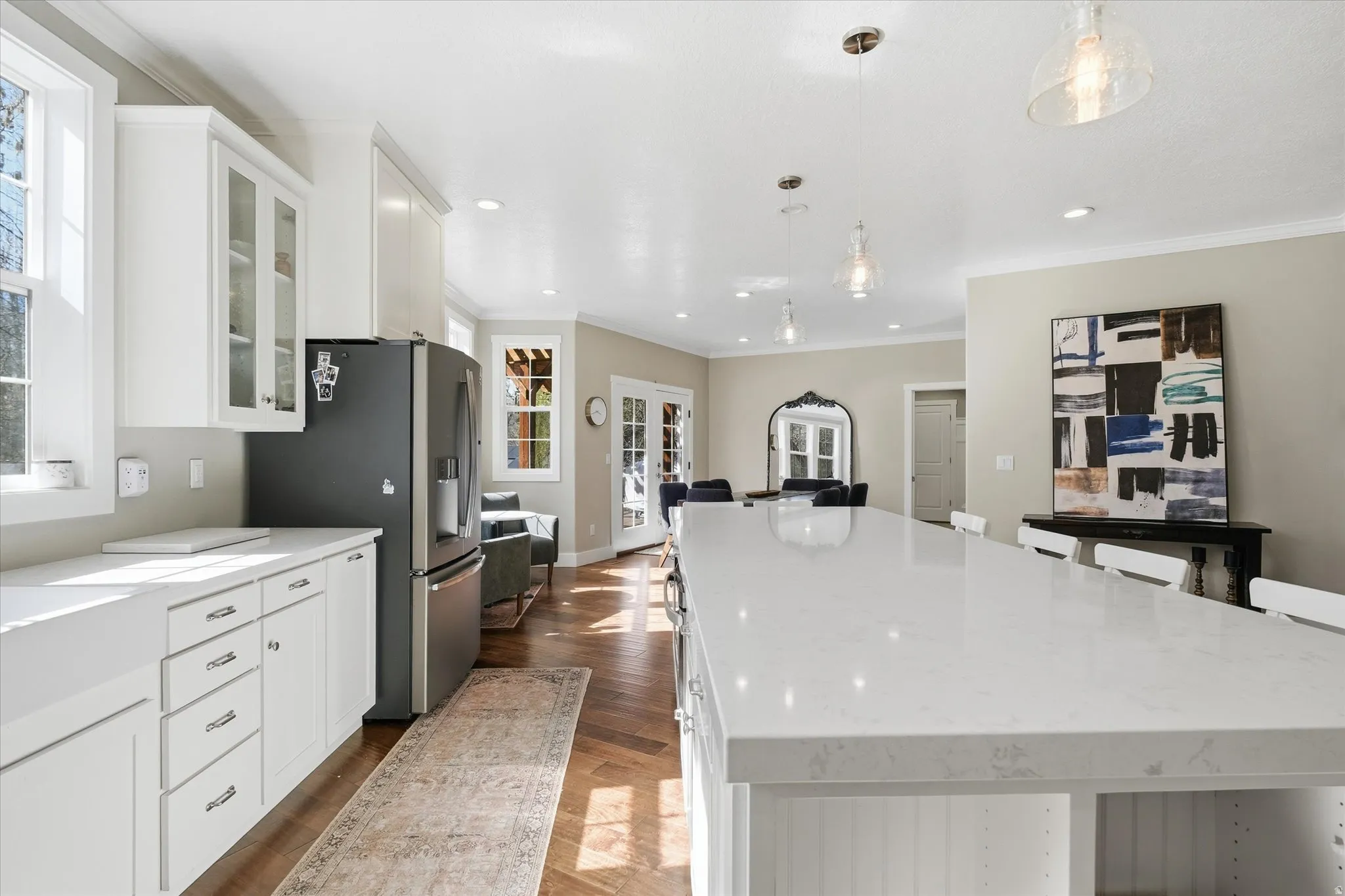 Kitchen featuring white cabinetry, light stone counters, a spacious island, a breakfast bar area, and pendant lighting