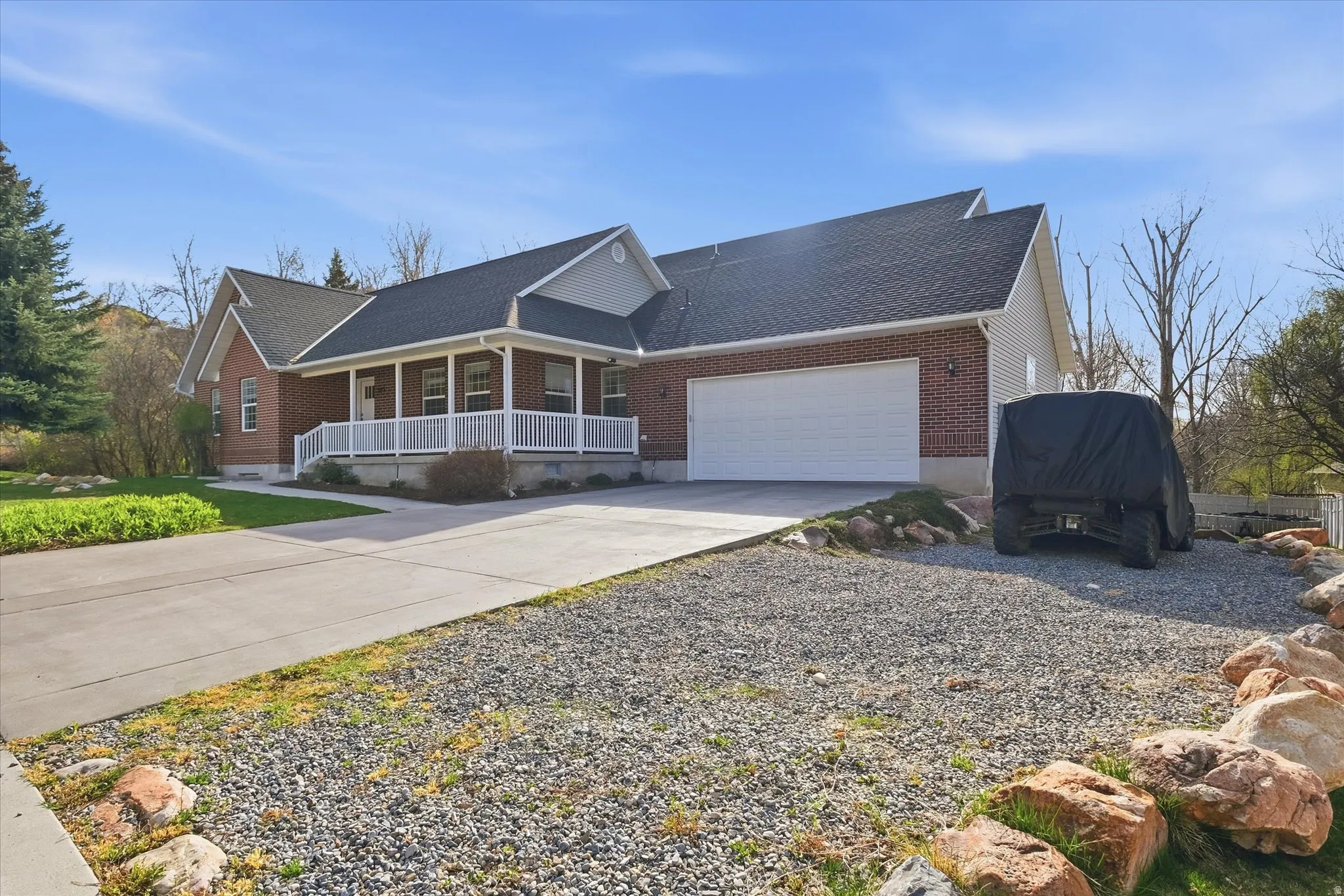View of front of property with covered porch, roof with shingles, concrete driveway, and brick siding