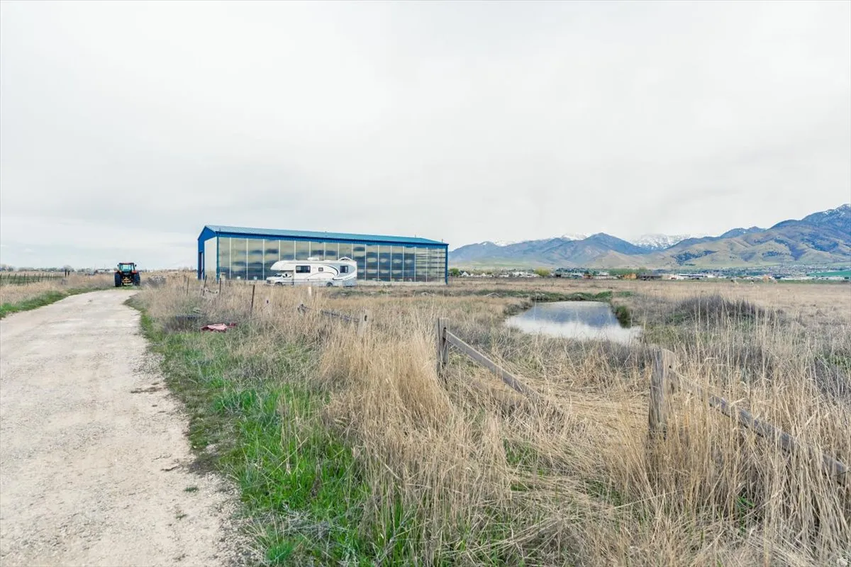View of dirt / gravel road featuring an outbuilding, a mountain view, and a view of rural / pastoral area