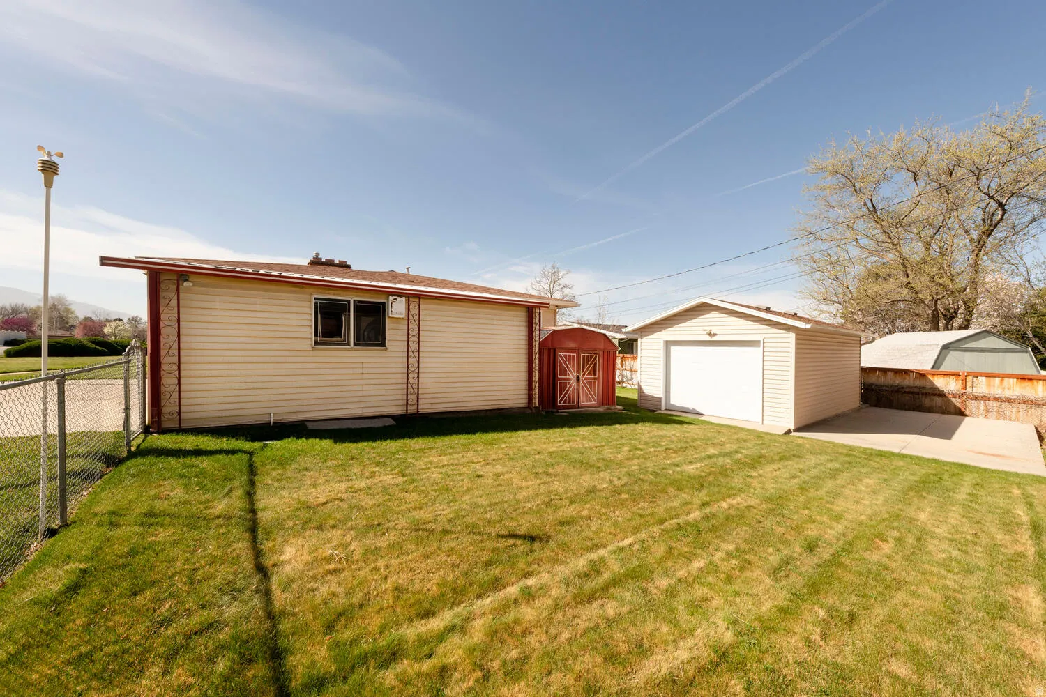 Fenced backyard with a detached garage and a storage shed