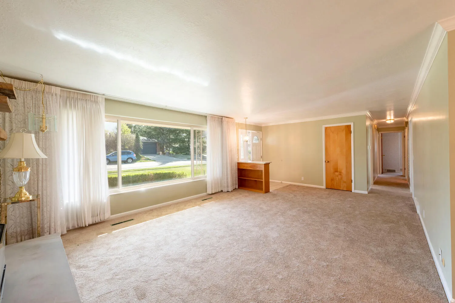 Unfurnished living room with light colored carpet and ornamental molding