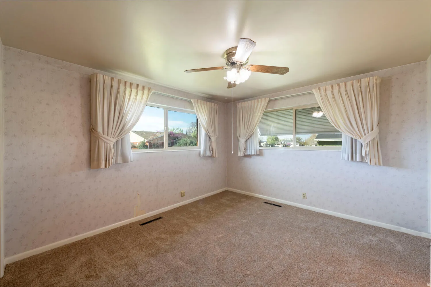 Carpeted spare room with wallpapered walls and a ceiling fan