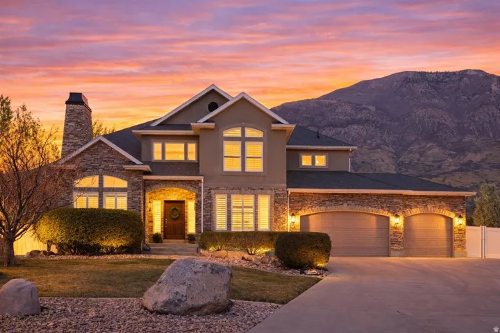 View of front facade with driveway, an attached garage, stucco siding, and a front yard