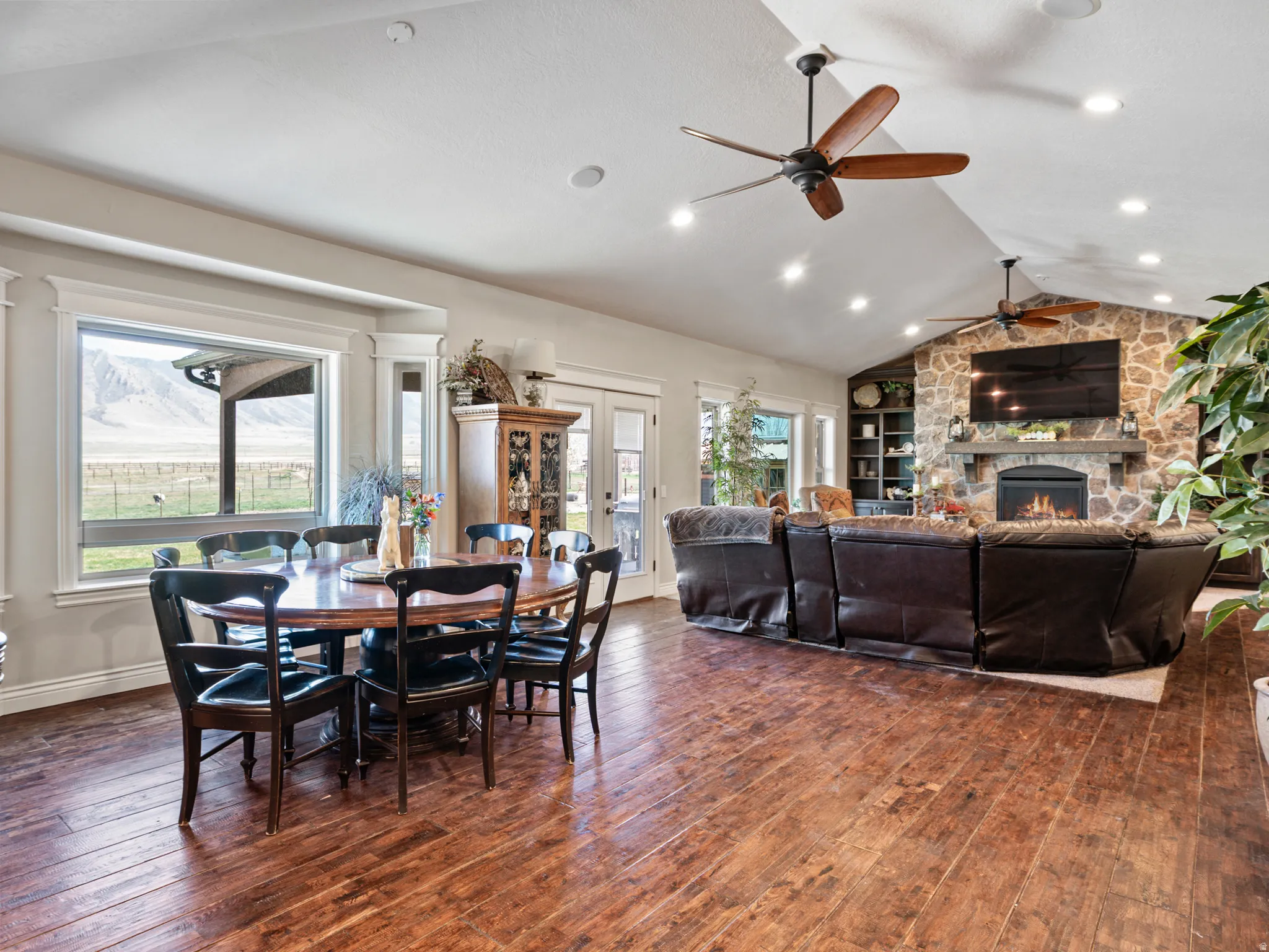 Dining area with dark wood-style floors, a stone fireplace, and french doors