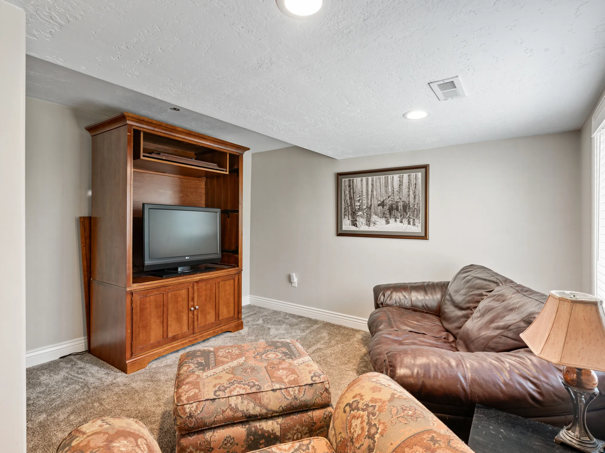 Living area with light colored carpet, a textured ceiling, and recessed lighting