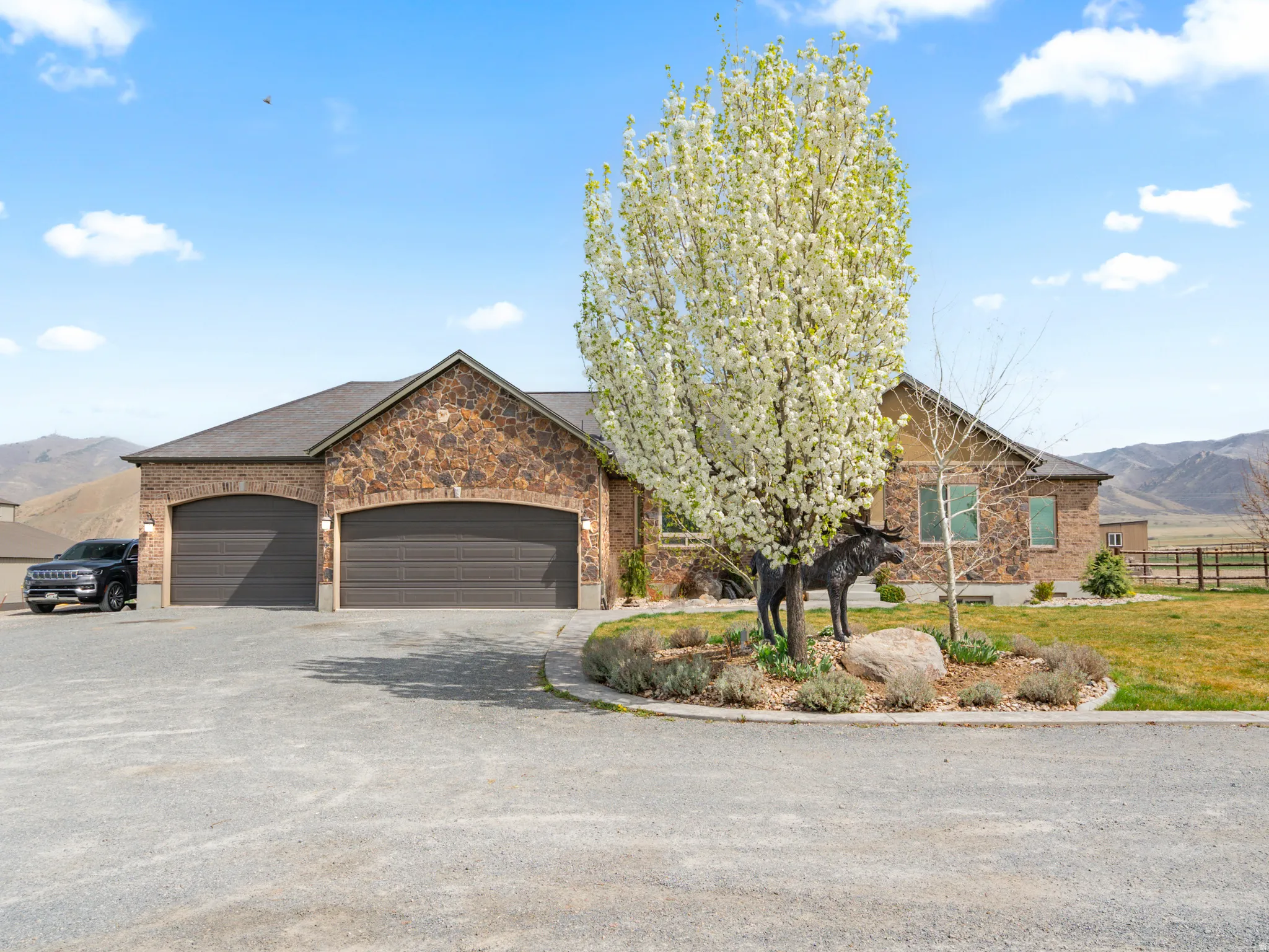 View of front of property with a mountain view, a garage, driveway, and brick siding