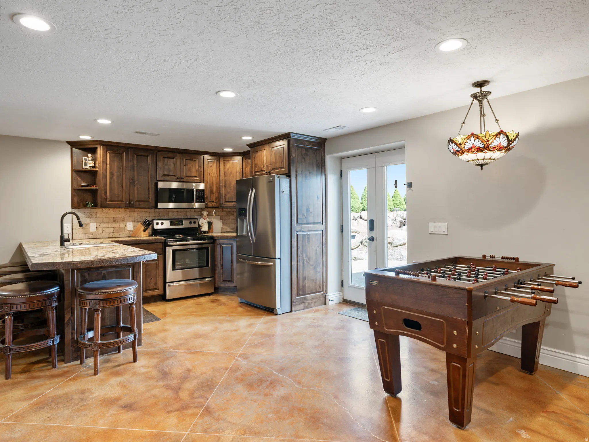 Kitchen with open shelves, stainless steel appliances, dark wood finish cabinets, a peninsula, and a breakfast bar area