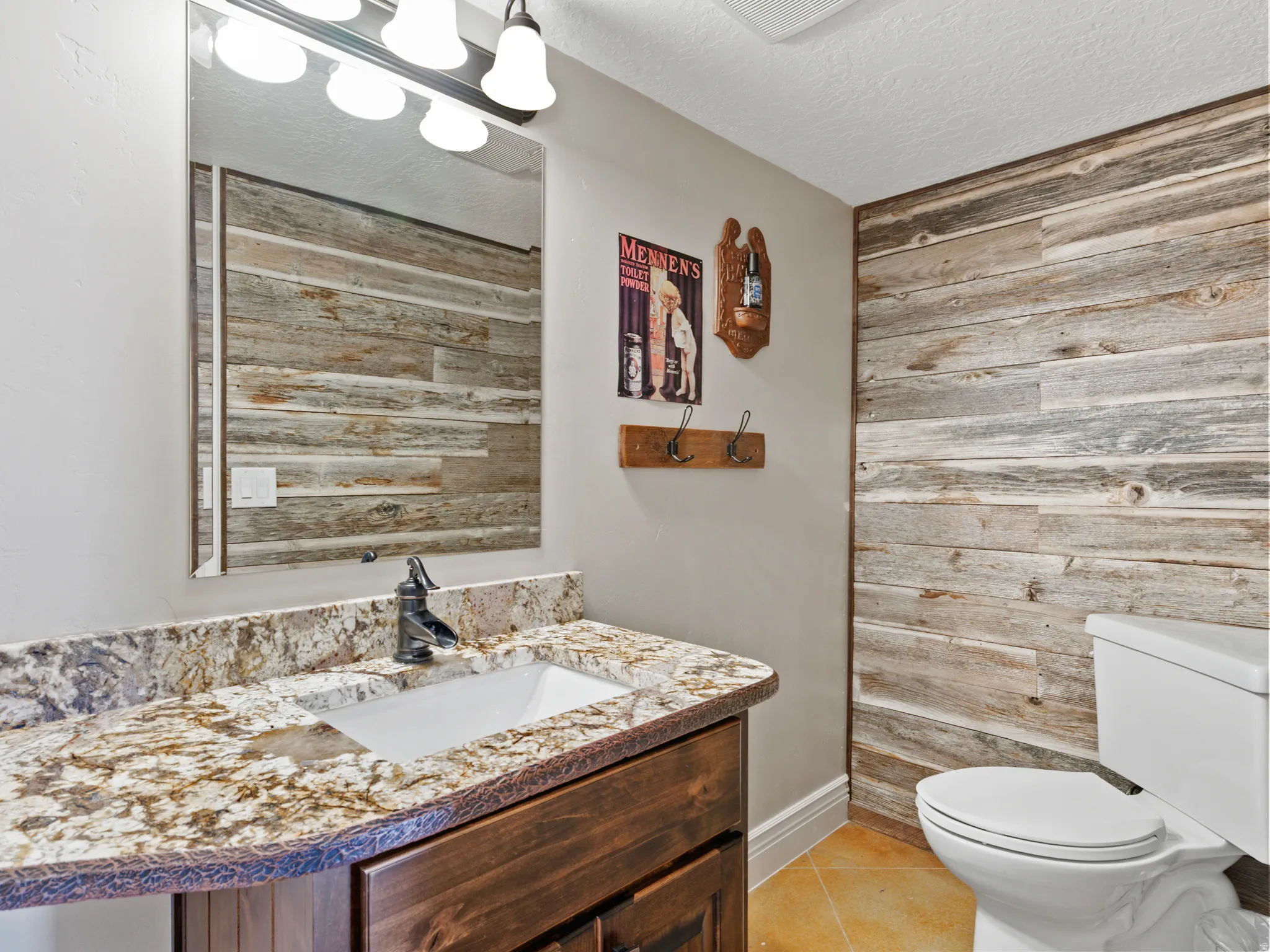 Half bath featuring vanity, light tile patterned flooring, wooden walls, and a textured ceiling