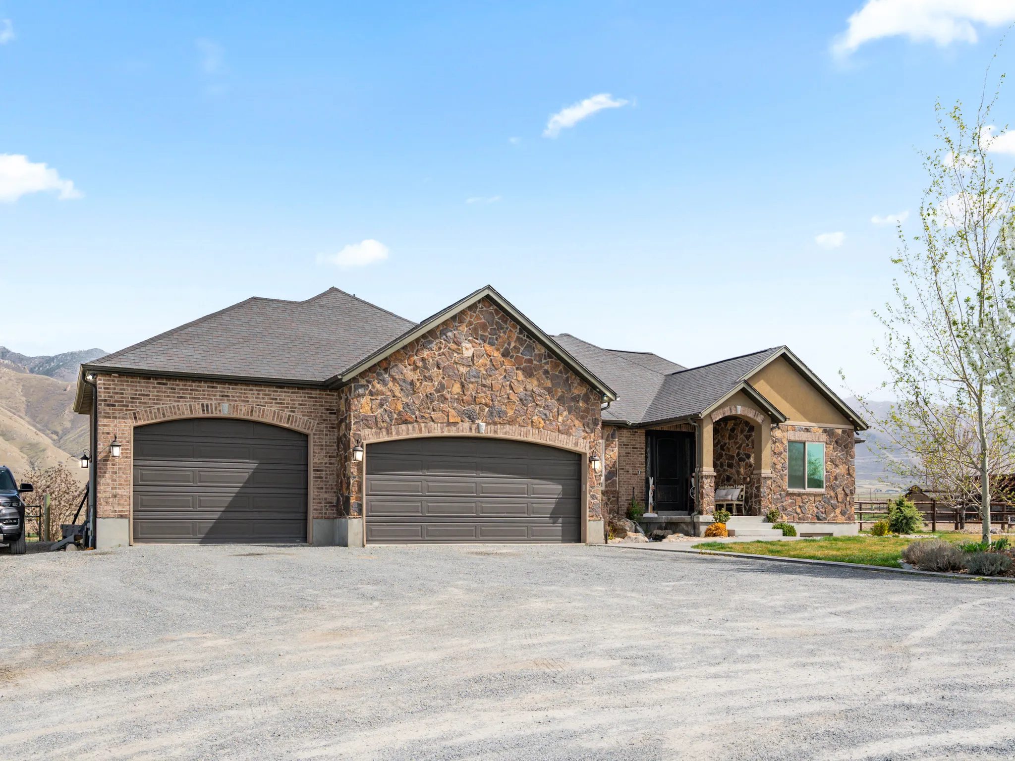 View of front of property with driveway, an attached garage, stone siding, and roof with shingles