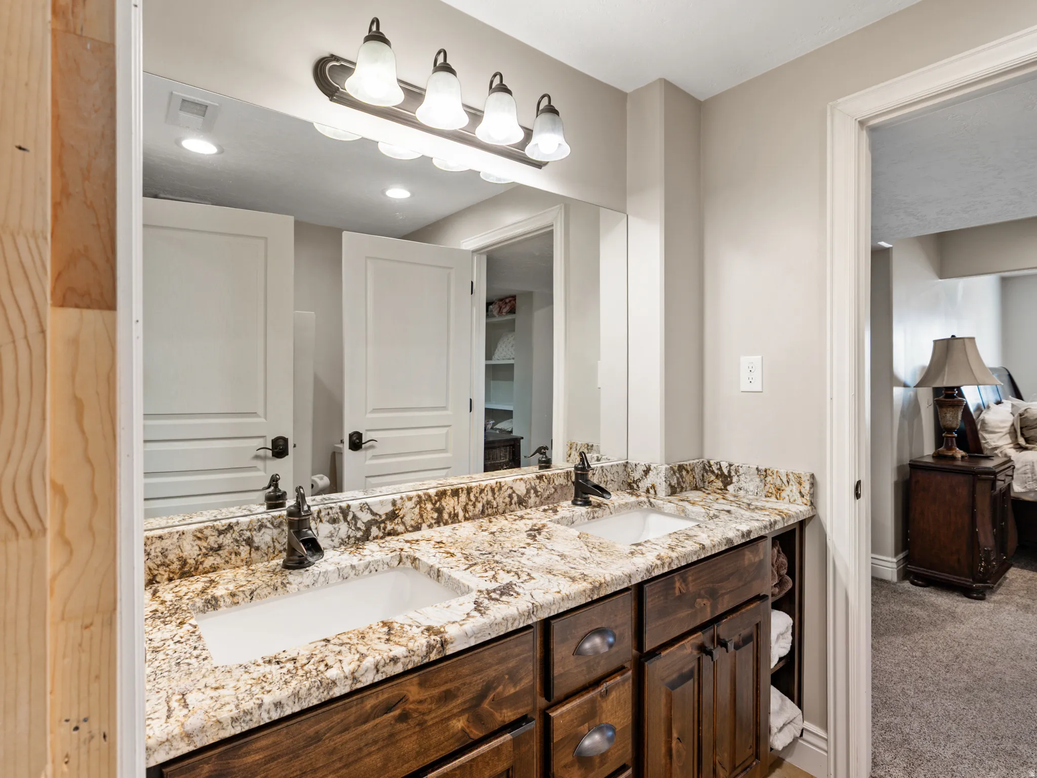 Bathroom with double vanity, light colored carpet, and recessed lighting
