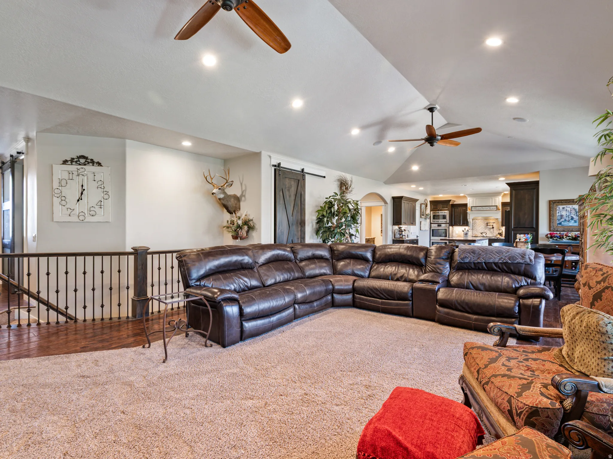 Carpeted living room with arched walkways, a barn door, a ceiling fan, vaulted ceiling, and recessed lighting