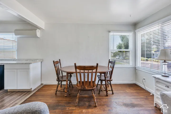 Dining area featuring wood-finish flooring, multiple large windows with blinds, and white walls