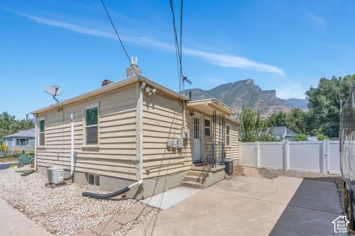 Rear exterior showcasing horizontal siding, a private concrete patio, and a white vinyl privacy fence