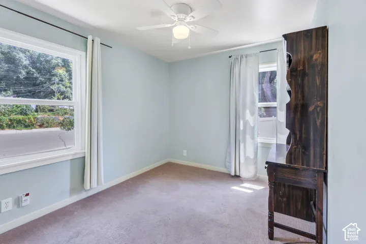 Carpeted room with a ceiling fan, light blue walls, and white trim