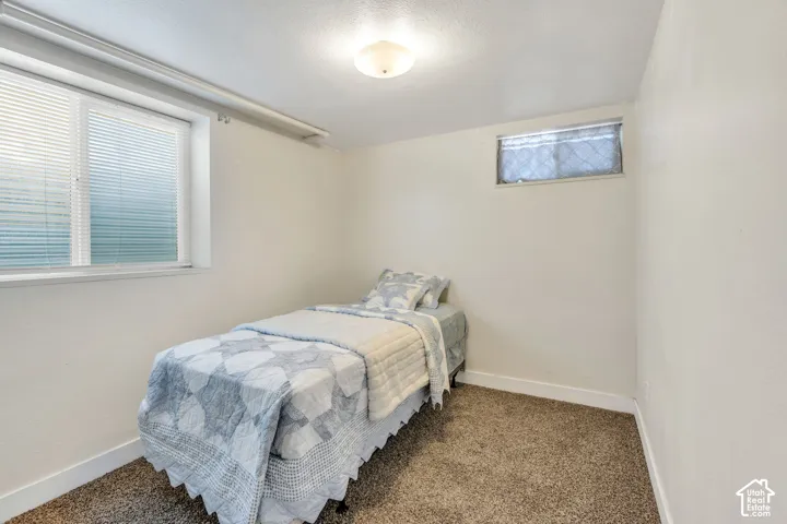 Room featuring textured walls, a ceiling-mounted light fixture, and plush carpet flooring