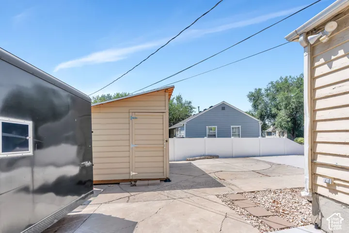 Concrete pad with a tan shed, white privacy fence, and gravel landscaping