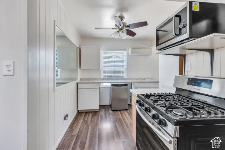 Kitchen featuring a stainless steel range, built-in microwave, white cabinetry, and wood-finish flooring