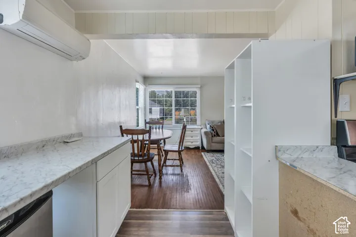 Kitchenette featuring white cabinetry, marble-finish countertops, and a built-in mini-split AC unit