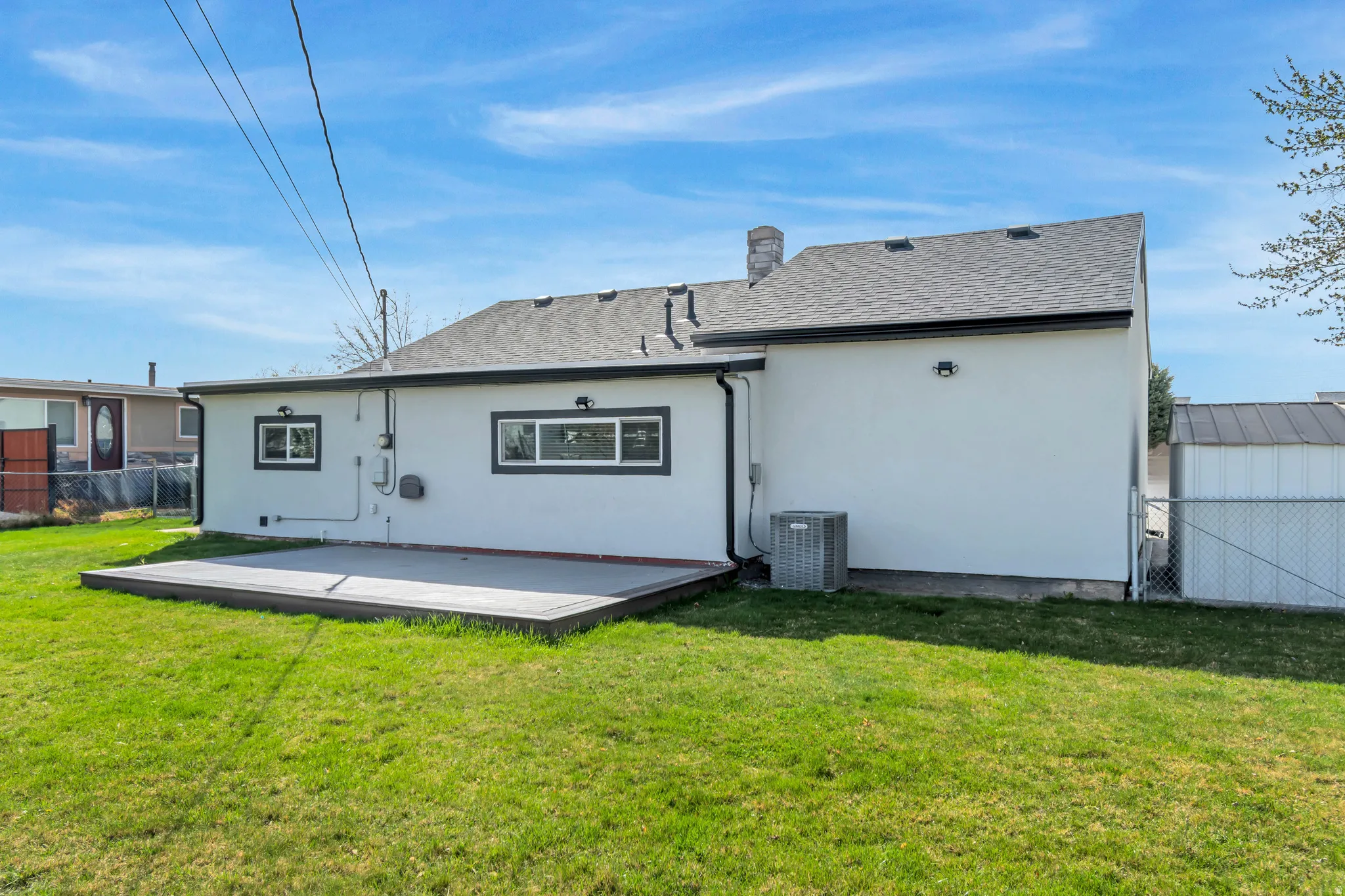 Back of house featuring a patio, stucco siding, a shingled roof, and a chimney