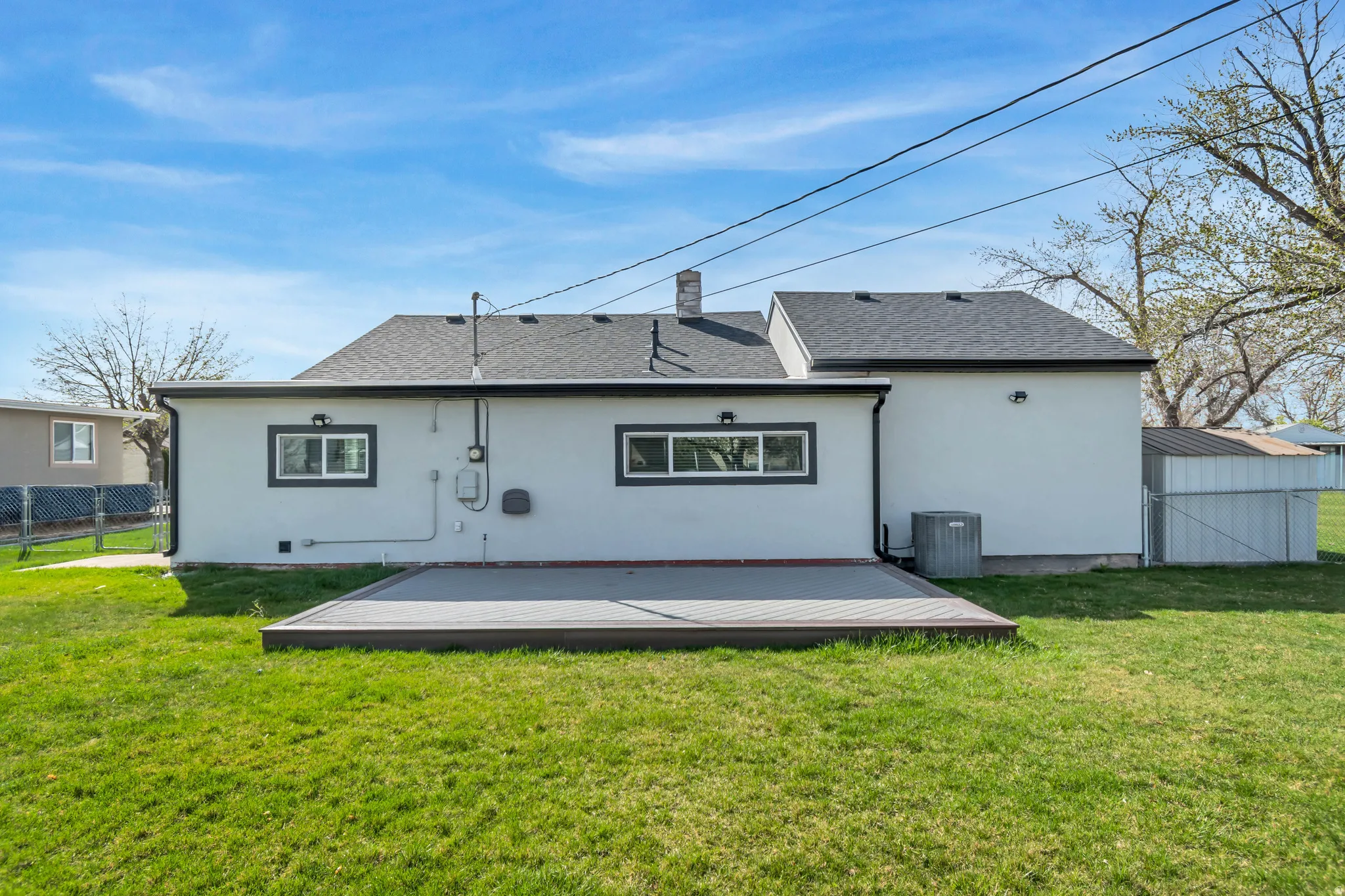 Back of property with stucco siding, roof with shingles, and a chimney