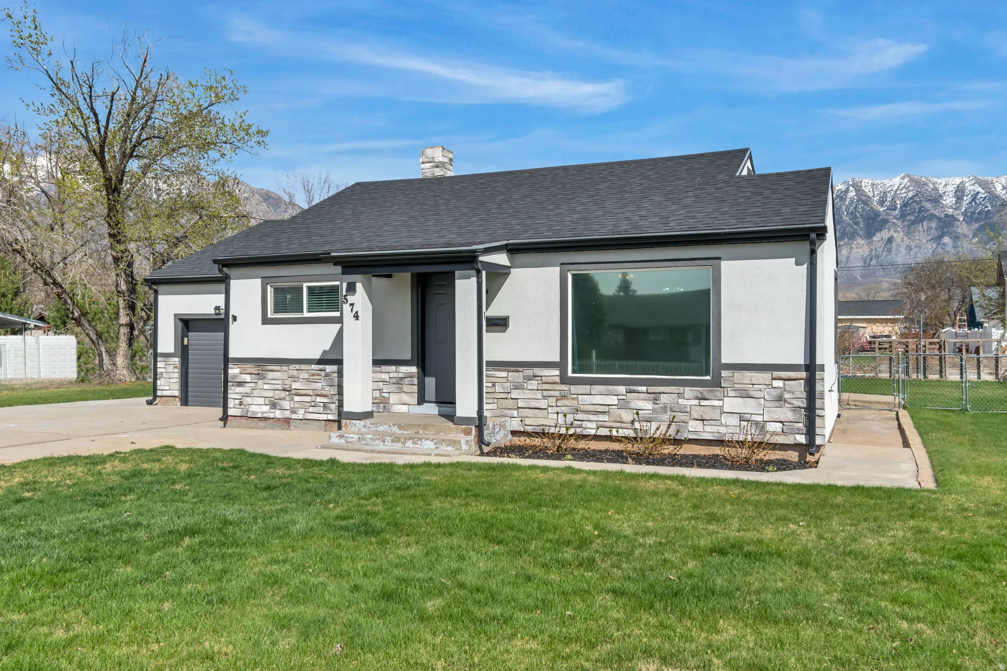 View of front facade with stucco siding, stone siding, a chimney, and a garage