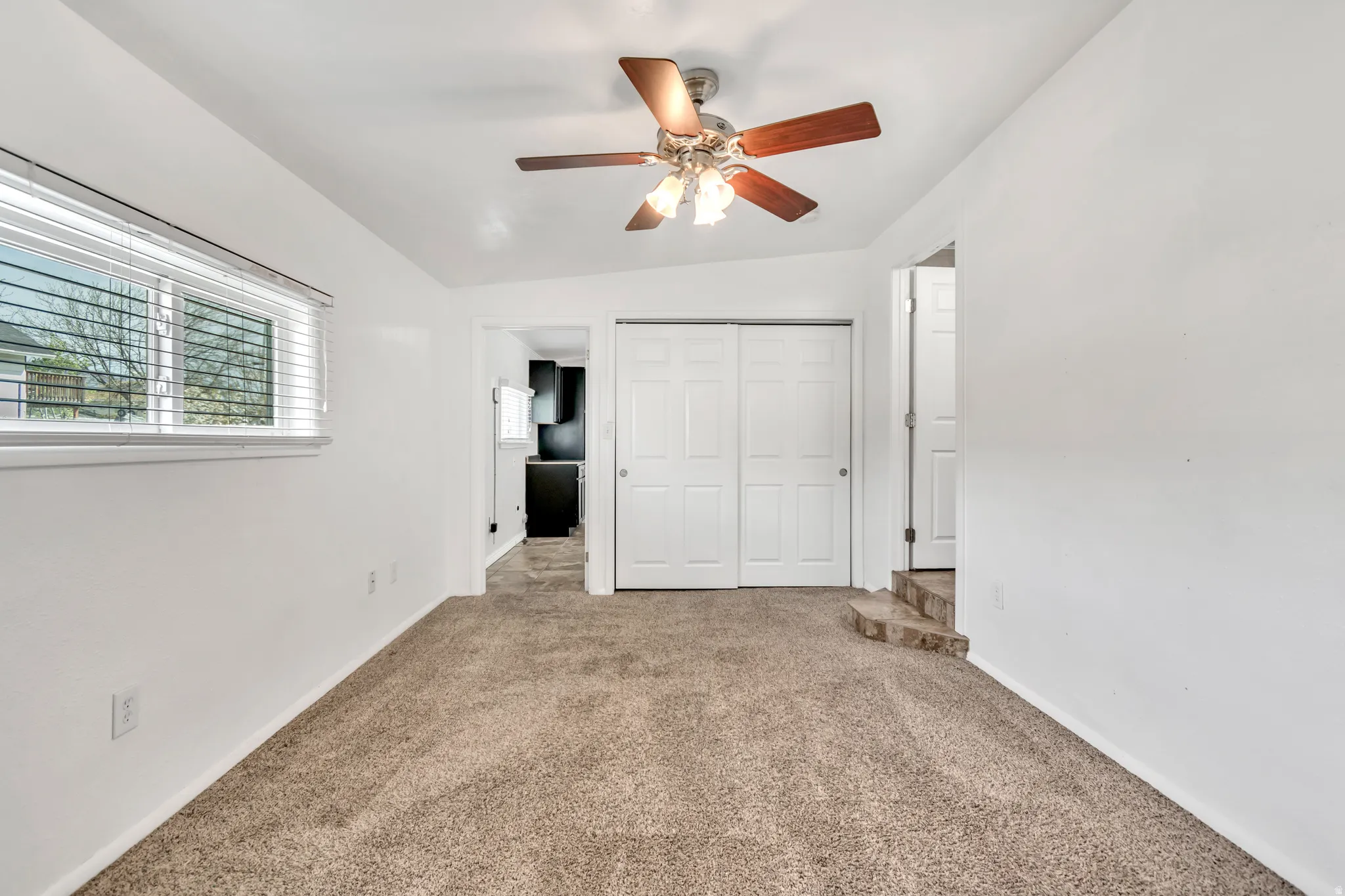 Unfurnished bedroom with carpet flooring, a closet, ceiling fan, and vaulted ceiling