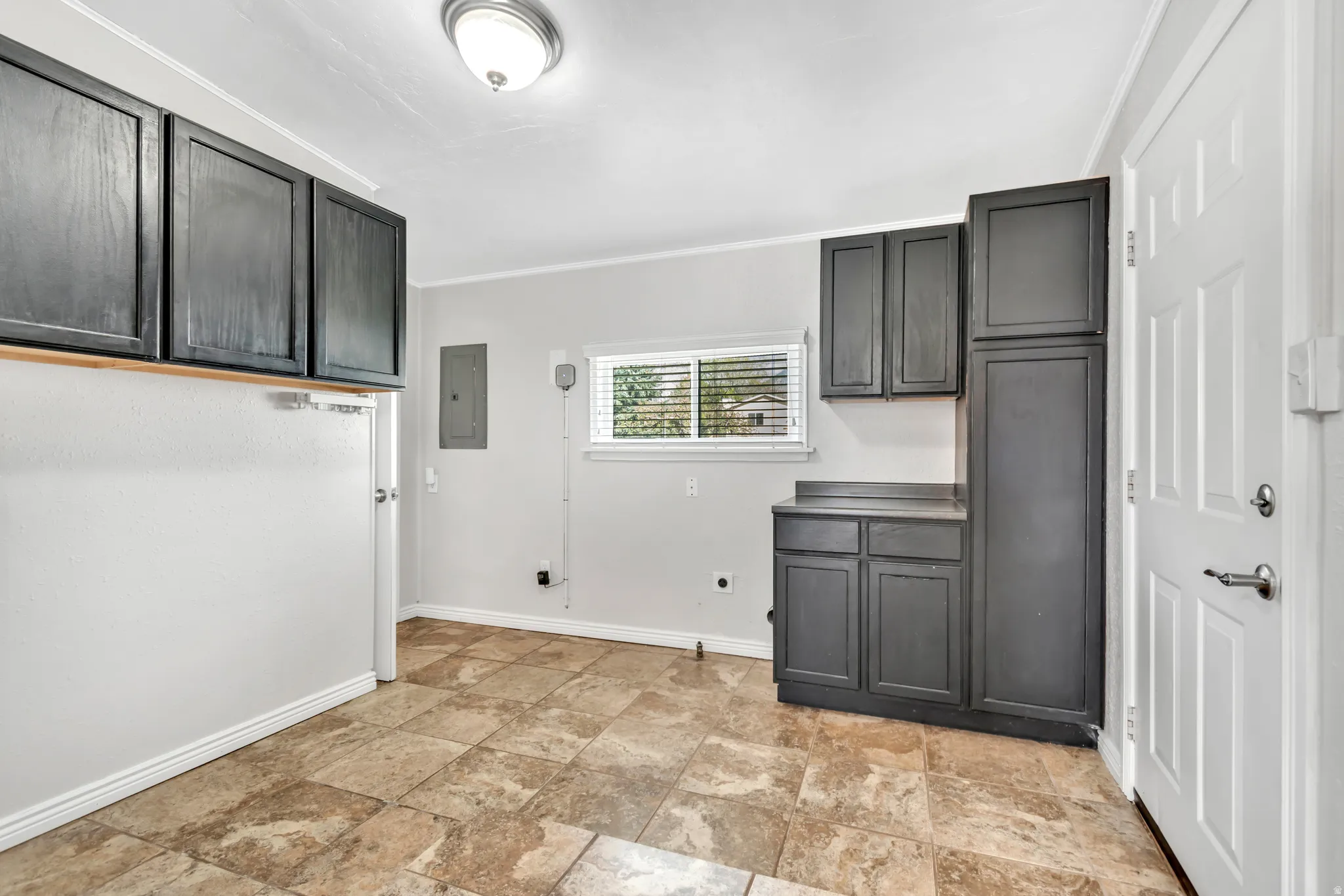 Laundry area featuring ornamental molding, cabinet space, electric dryer hookup, stone finish floors, and electric panel